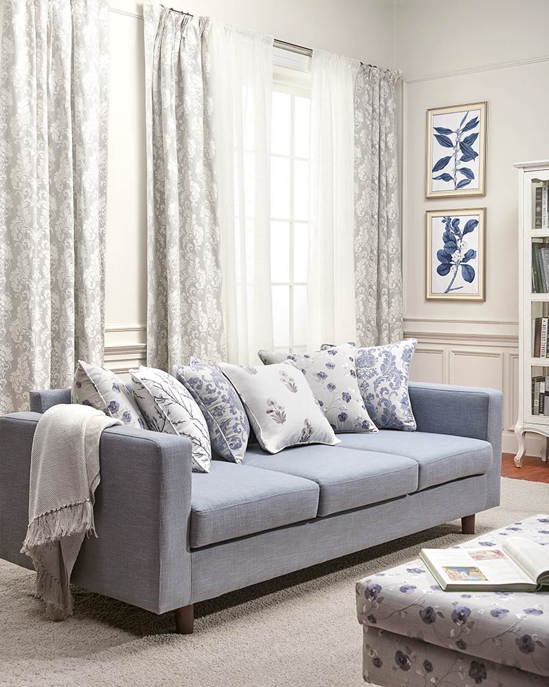 Living room with a sofa, cushions, curtains, and framed artwork on the wall