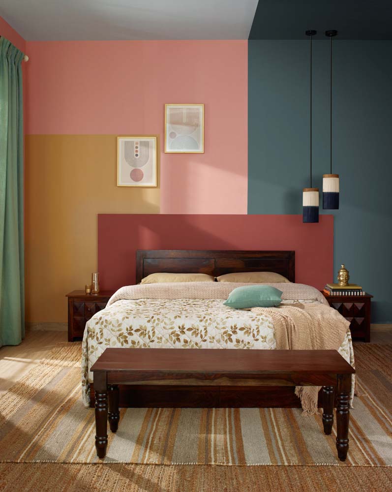 Multi coloured bedroom with a wooden bed, hanging lights and artworks