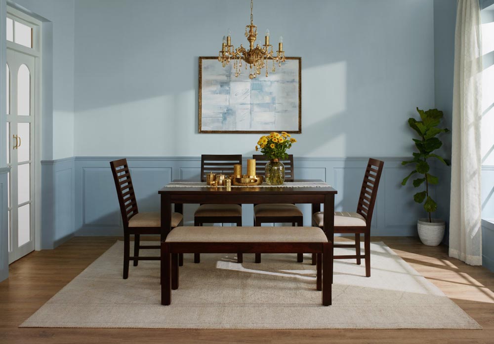 A blue room with a wooden six seater dining table with a bench