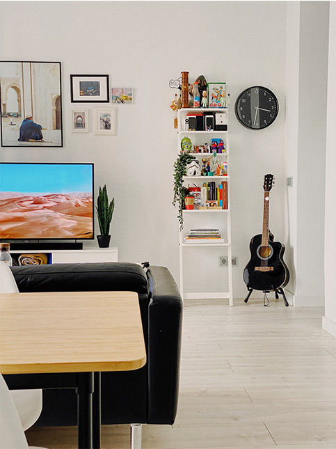 A white living room with a black sofa and a black guitar