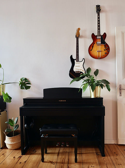 A white room with wooden flooring and a black guitar