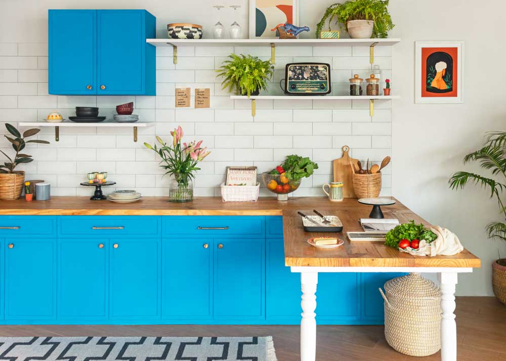 A white kitchen with blue cabinets, wooden countertops and white tiles as backsplash