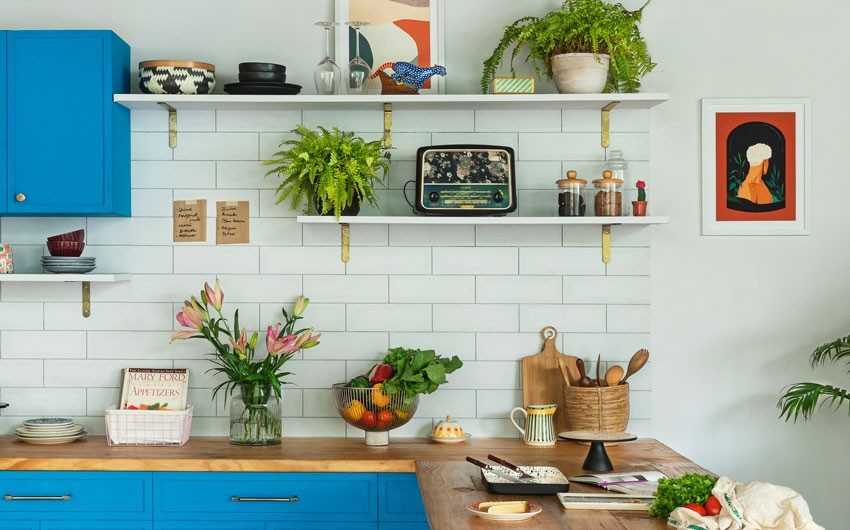 A white kitchen with blue cabinets, wooden countertops and white tiles as backsplash