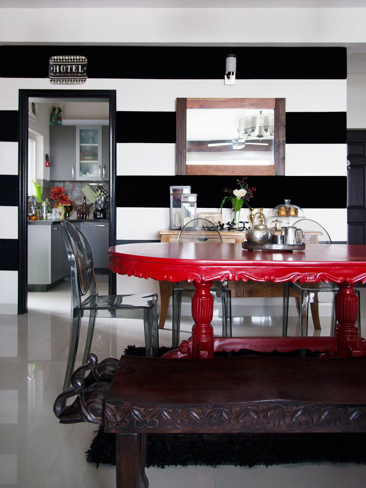 Red teakwood dining table, black and white walls and transparent chairs in Barooah's Bangalore house