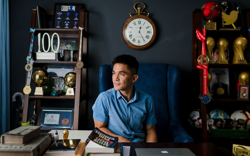 Footballer Sunil Chhetri Sitting on a chair at his home office in his home in Bengaluru with his trophies and medals kept in a couple of display units