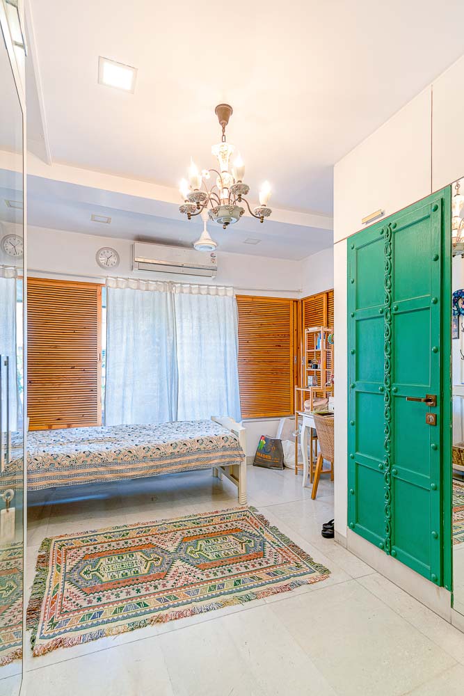 A room with a traditional green door, a embroidered carpet and a bed