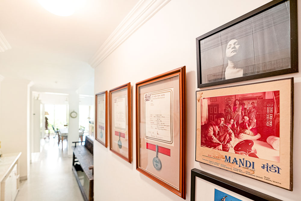 A corridor with a wall with medals framed in a wooden frame, a photo and a poster of the film 'Mandi'