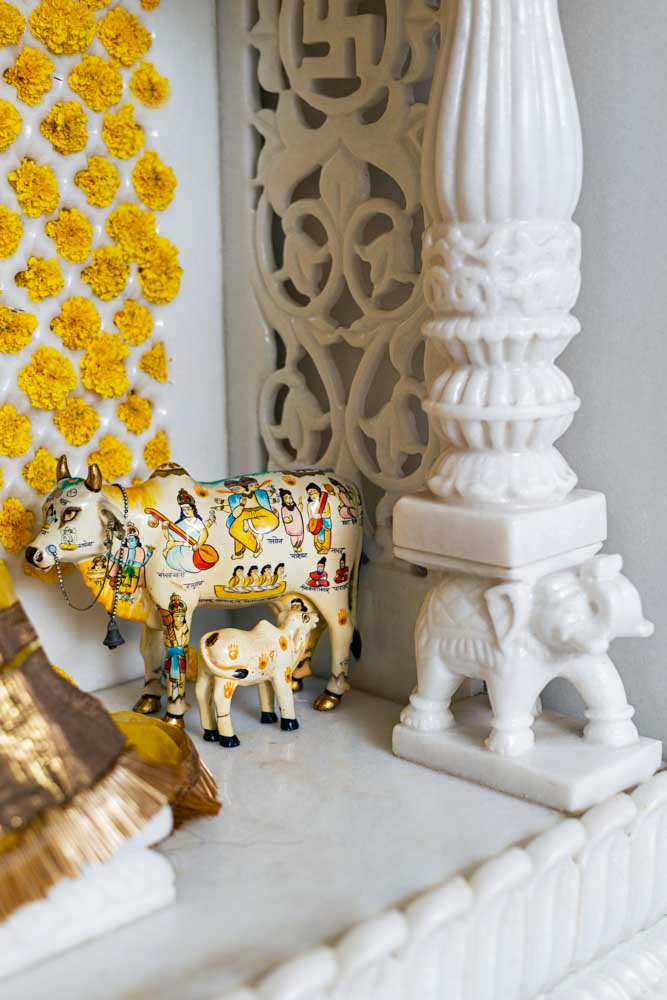 A stature of a cow and a calf placed in the corner of a pooja room