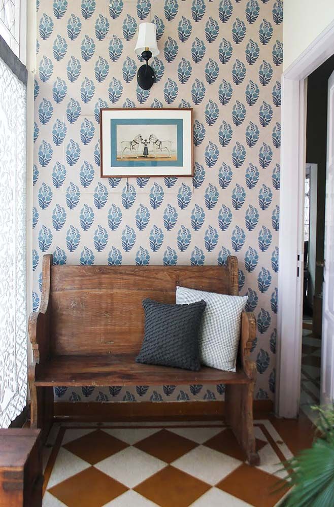 A wooden bench beside a window with the walls covered with a blue wallpaper - Beautiful Homes