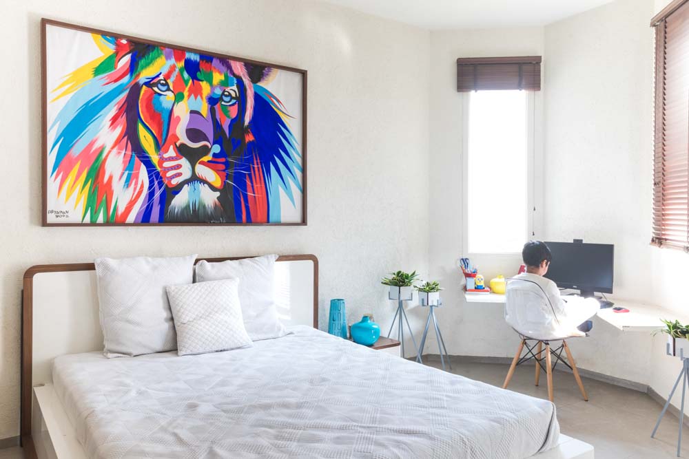 A white bedroom with a large colourful artwork