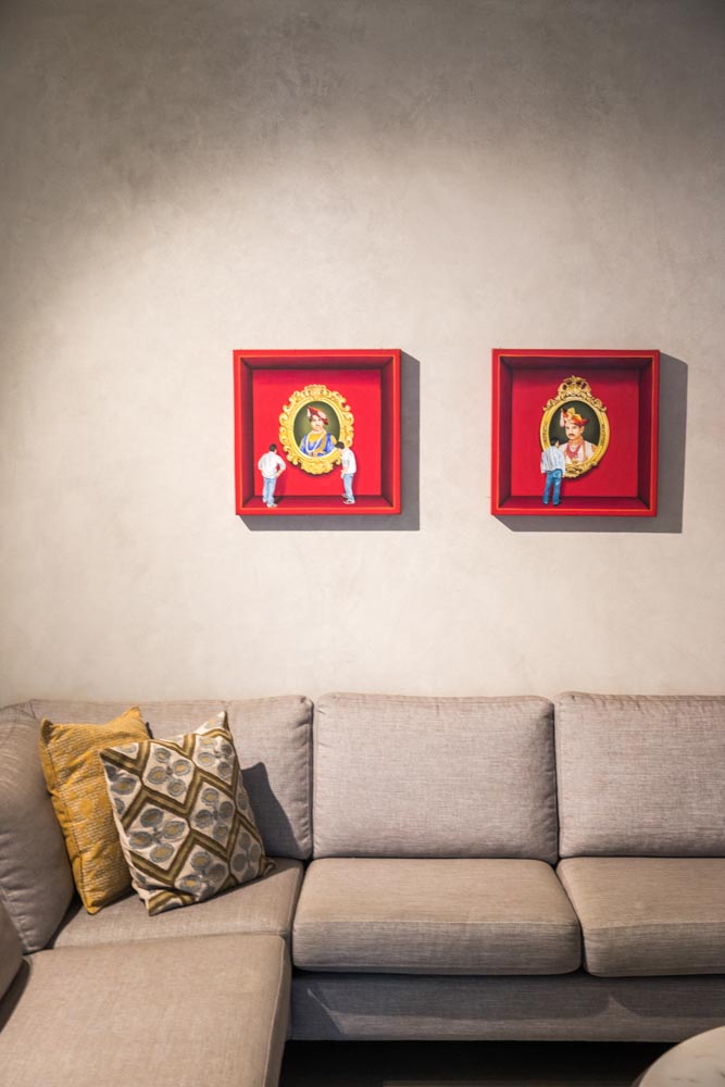 Two red artworks placed above a grey L-shaped sofa