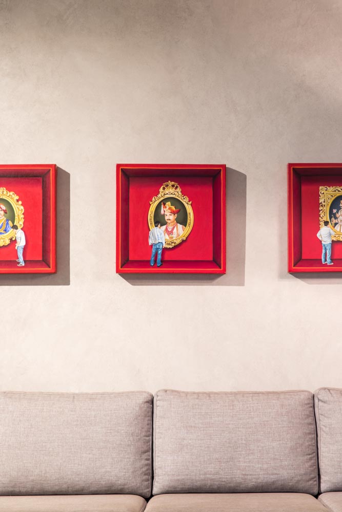 Three red artworks placed above a grey L-shaped sofa