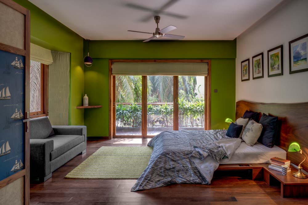 A bedroom with green colour walls, a sofa and a bed