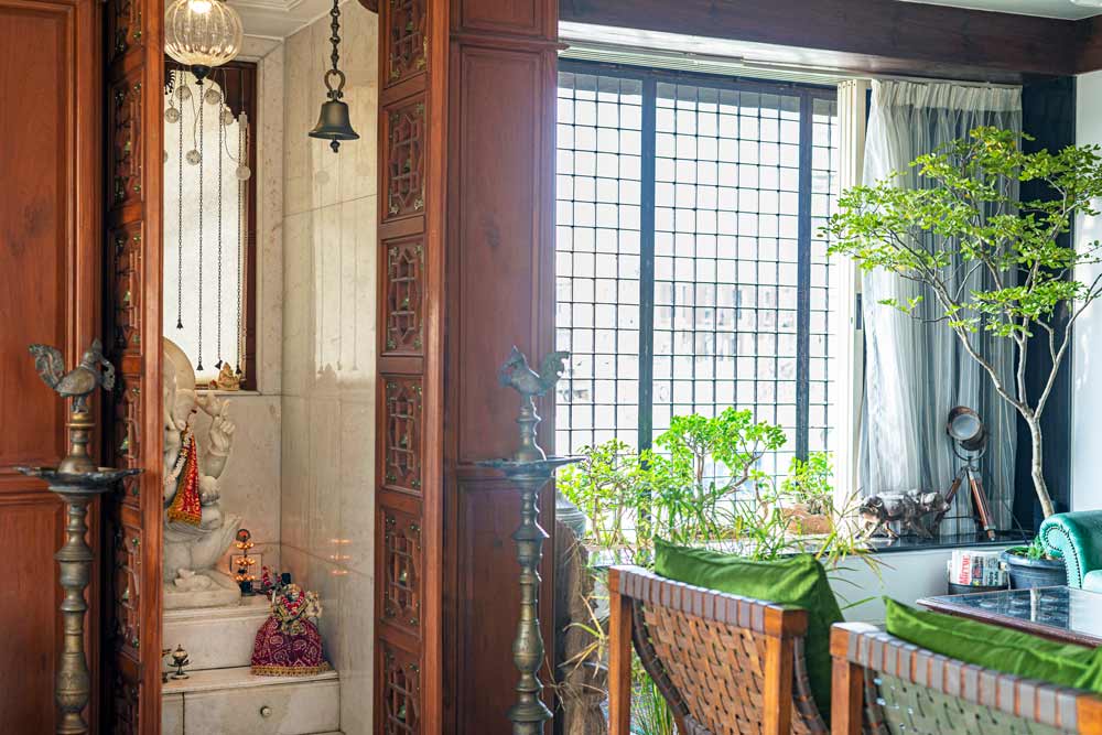 A pooja room with a wooden door and two tall brass lamps placed on both sides of the door - Beutiful Homes