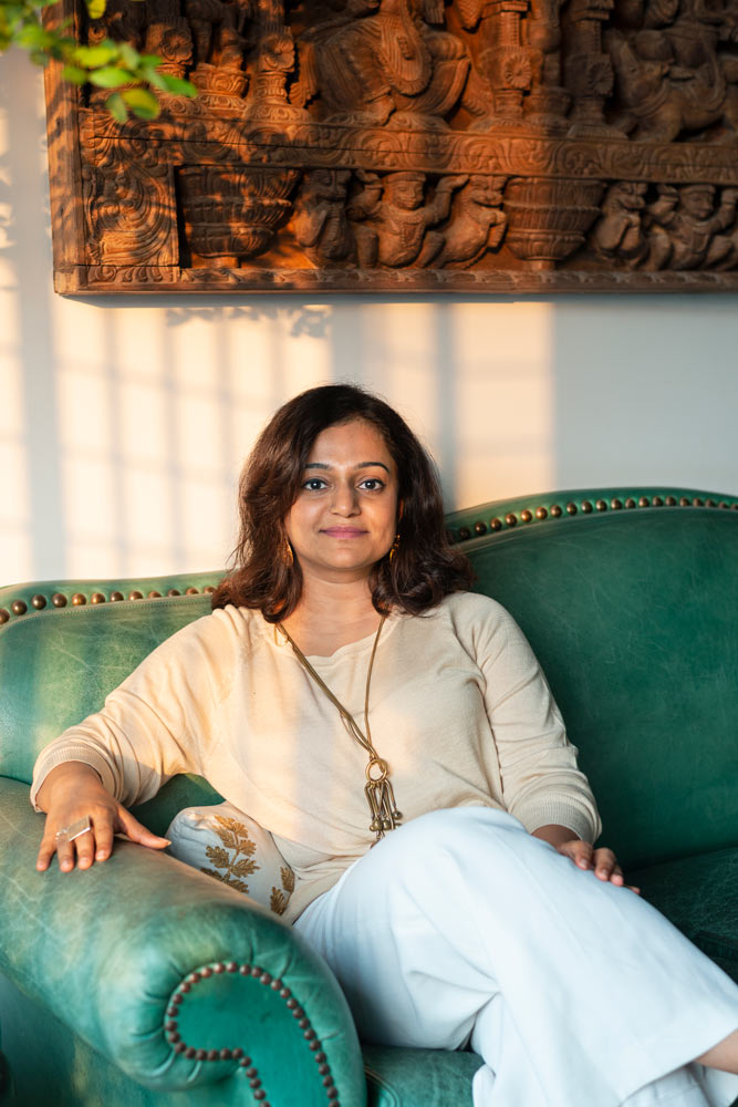 Amritha karnakar sitting on a green sofa in her living room
