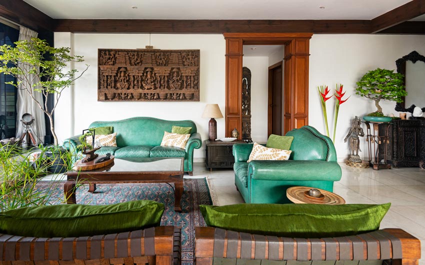 A living room with a green sofa and a wooden artwork behind it