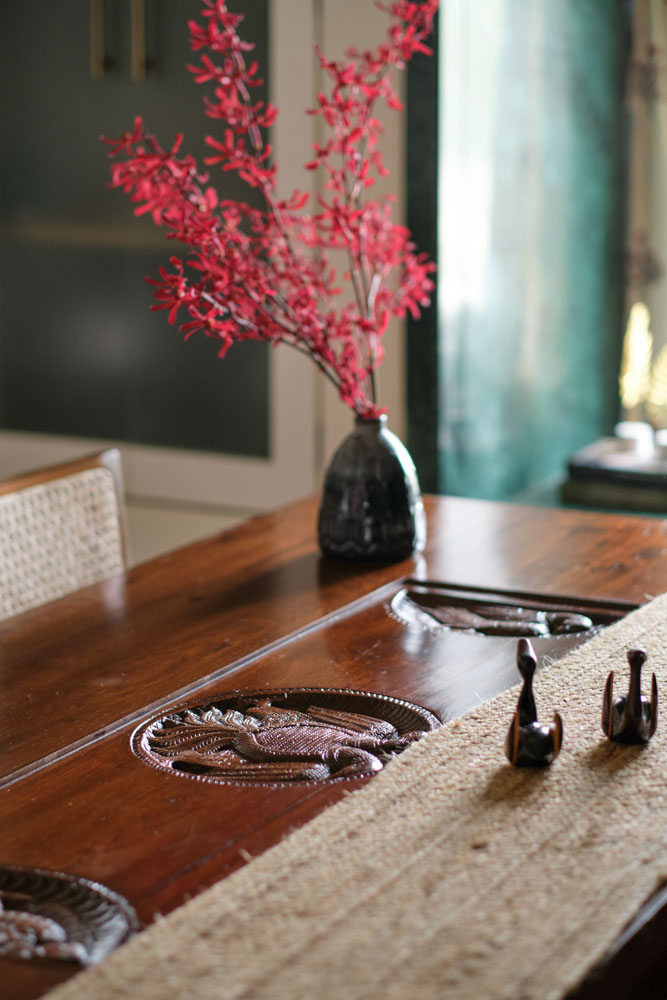 The tabletop of the teakwood dining table has a hand - carved panel - Beautiful Homes