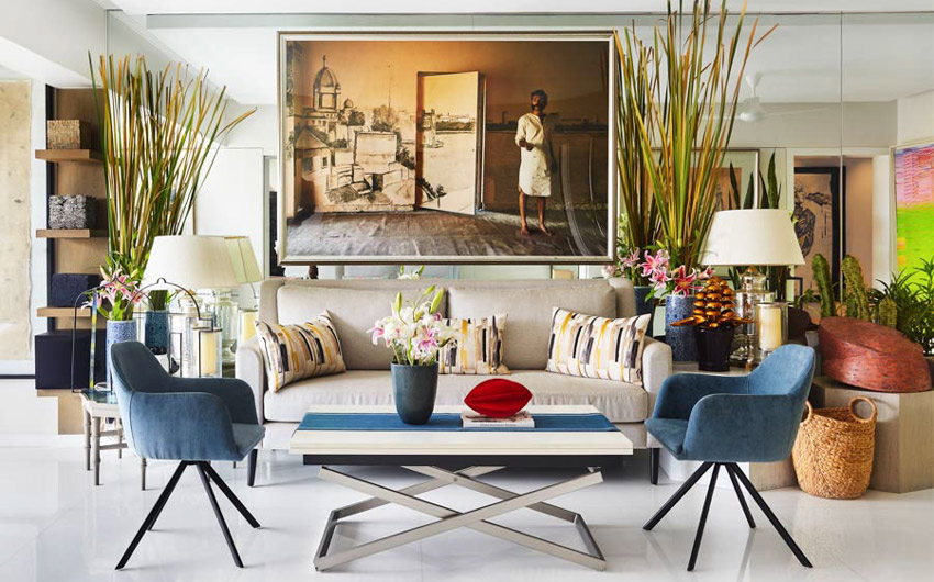 Living room with a white sofa, two identical blue chairs and a large artwork on the wall behind the sofa