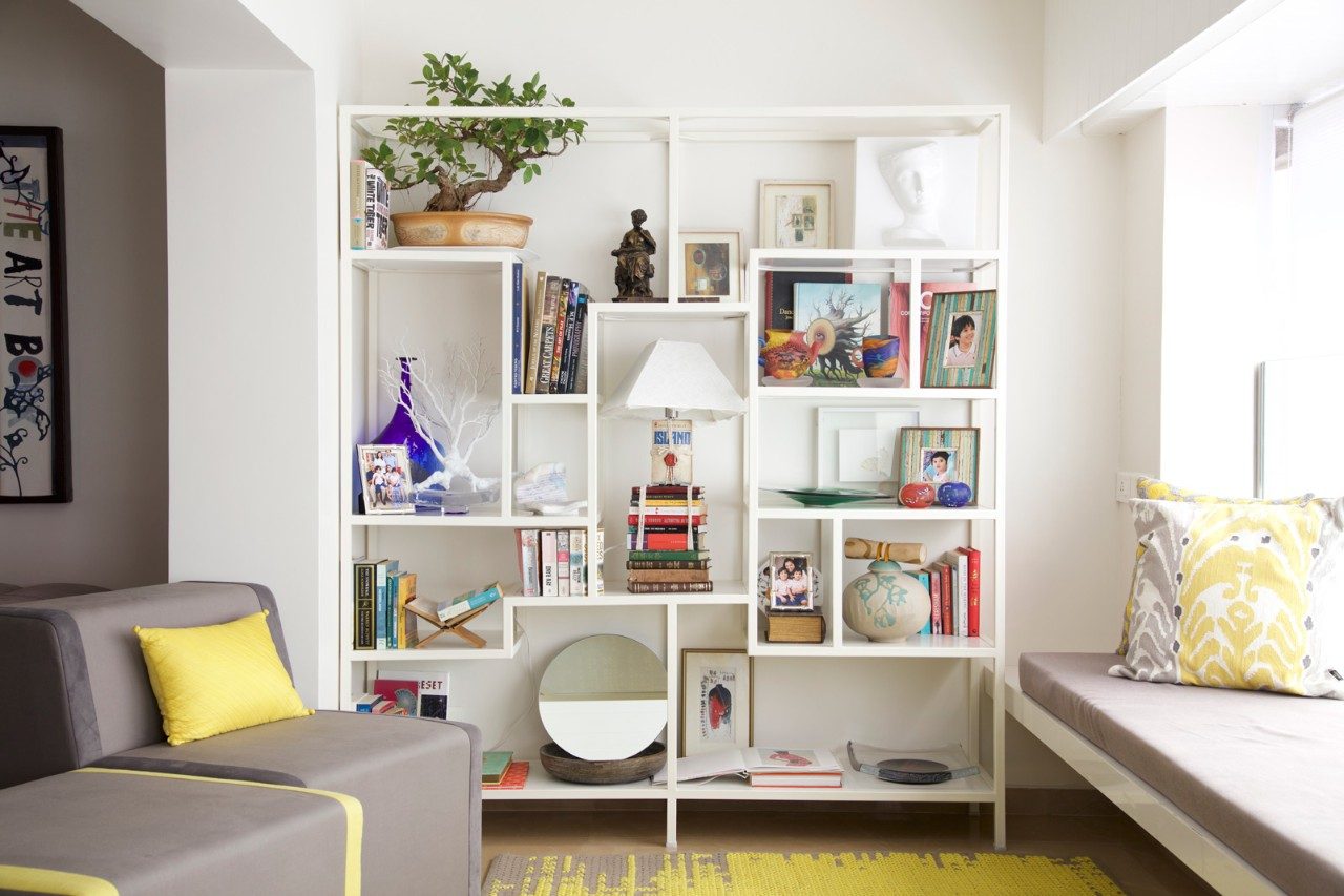 A sleek bookshelf placed to utilise the empty space between two pillars - Beautiful Homes