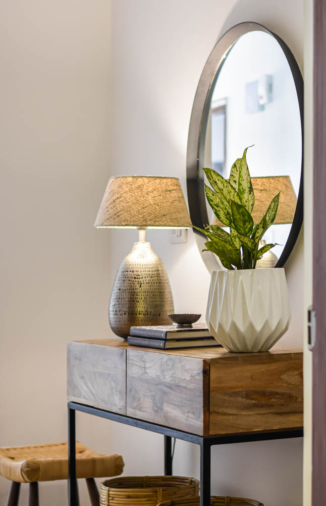 Small console with a mirror, table lamp & indoor plant at the entryway - Beautiful Homes