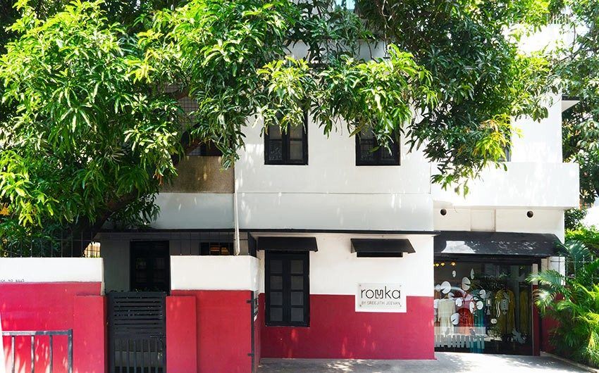 A 2 storeyed building painted in white and red with a mango tree in front of it - Beautiful Homes
