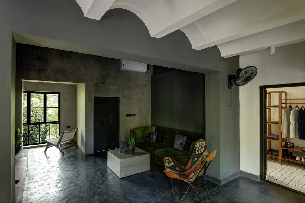 An entertainment room with a green sofa and concrete finish - Beautiful Homes