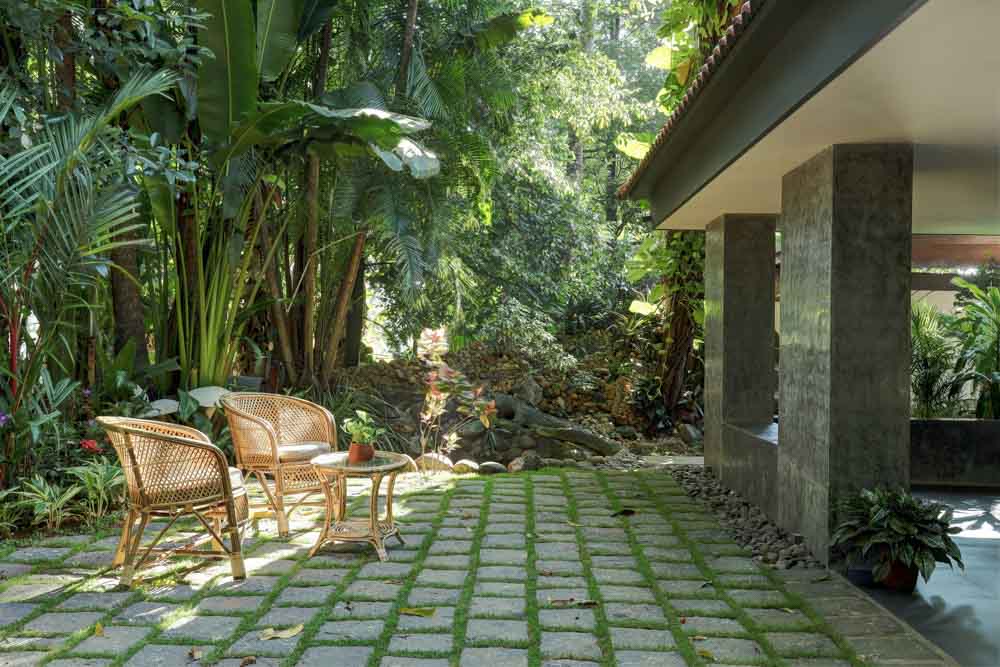 A courtyard of a house with a couple of cane chairs and a centre table - Beautiful Homes