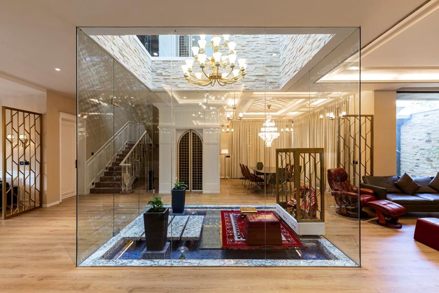 A glass encased puja room with a skylight and a chandelier - Beautiful Homes