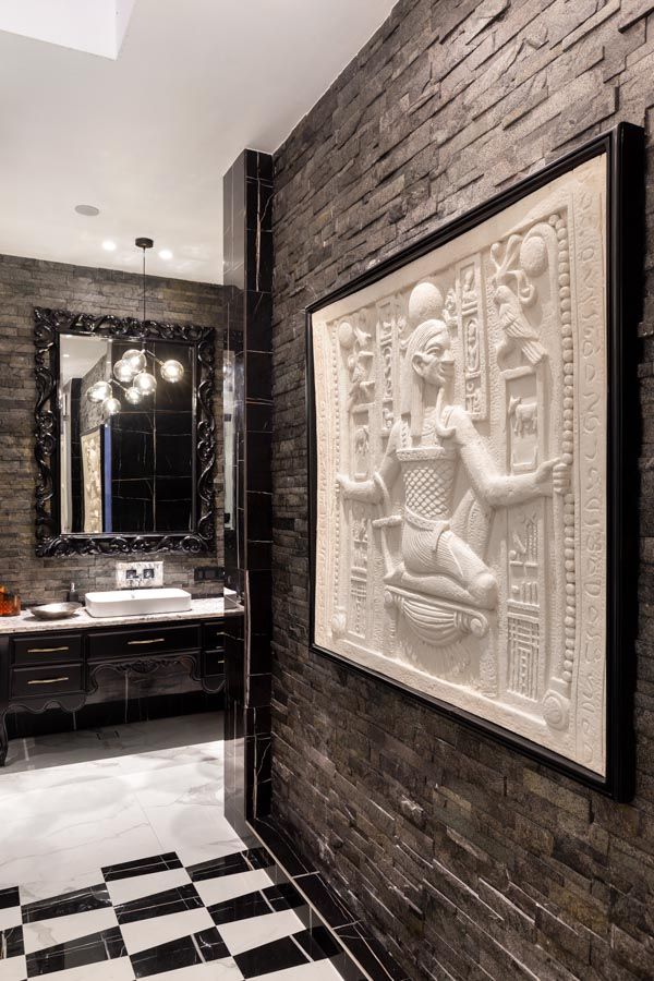 A Egyptian inspired wall mural at the entrance of a bathroom with black and white tiles - Beautiful Homes