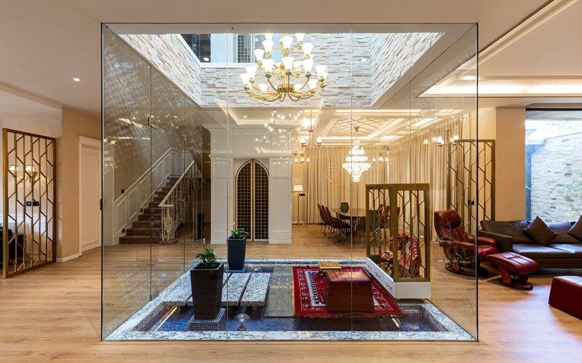 A glass encased puja room with a skylight and a chandelier - Beautiful Homes