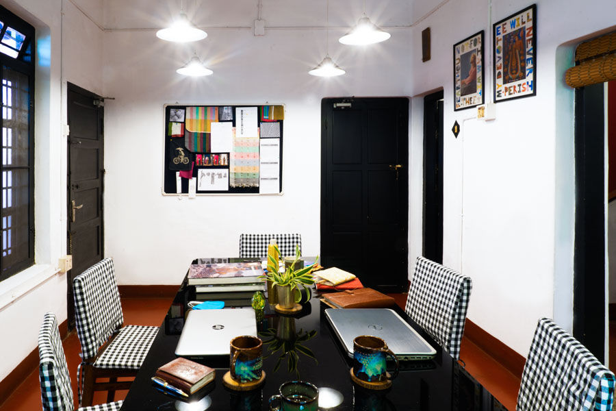An office with a black table on which there are a couple of laptops, a small planter, 3 coffee mugs and some books - Beautiful Homes