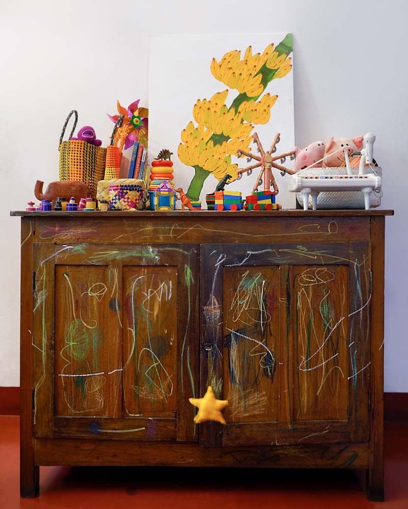 A vintage wooden cabinet with crayon marks on its surface, and on which there is a painting and some toys - Beautiful Homes