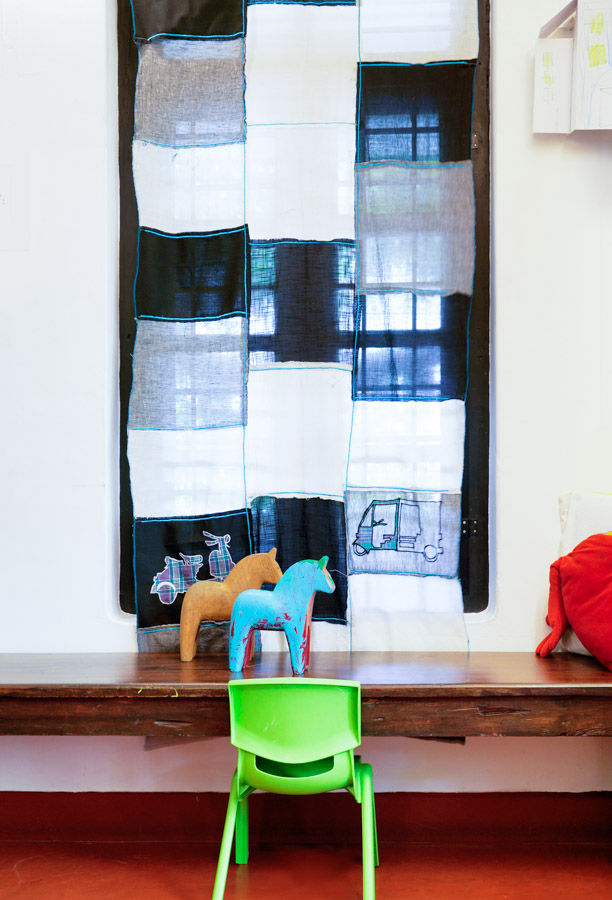 A small bright green chair kept in front of a window with a black and white curtain - Beautiful Homes