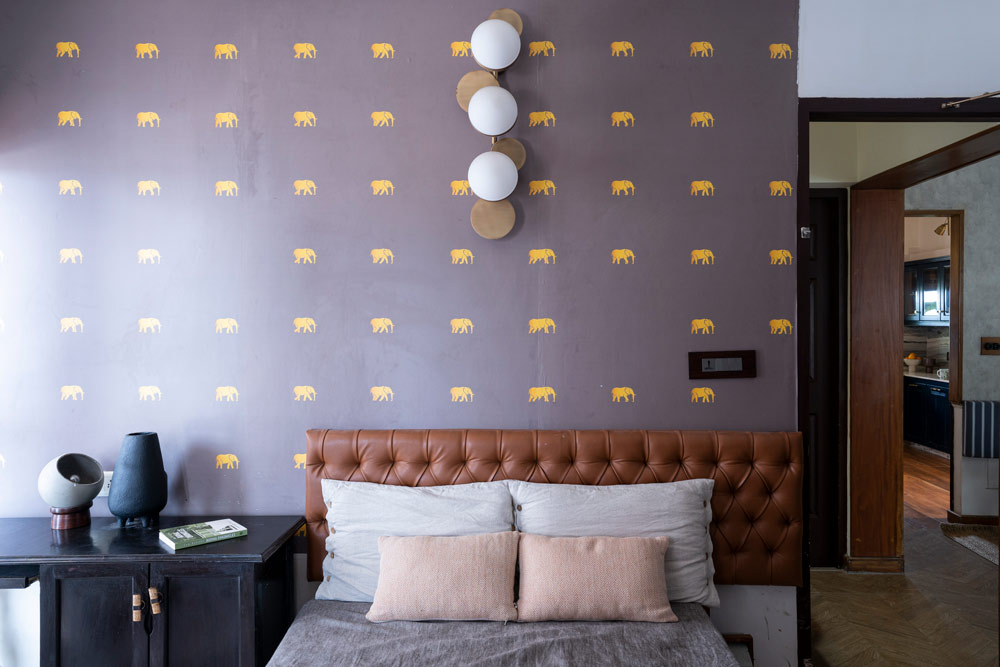 The guest bedroom design has wall globe lamp & has leather headboard - Beautiful Homes