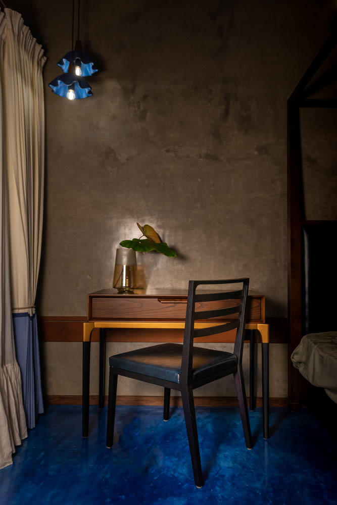 Wooden study table, chair & hanging light with blue oxide floor & polished plastered wall - Beautiful Homes