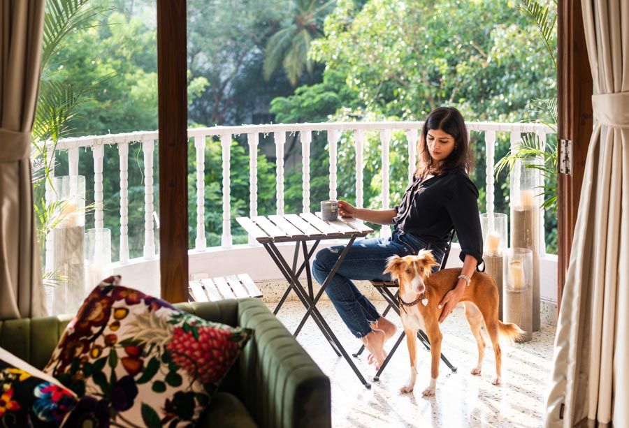 Sarah Sham sitting on her balcony with a mug and a dog, lush green garden in the background - Beautiful Homes