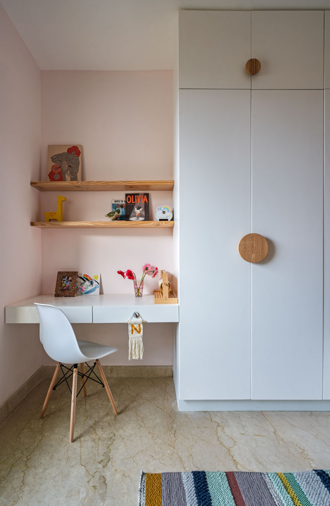 A kids room with a study table in a corner and next to it is a wardrobe