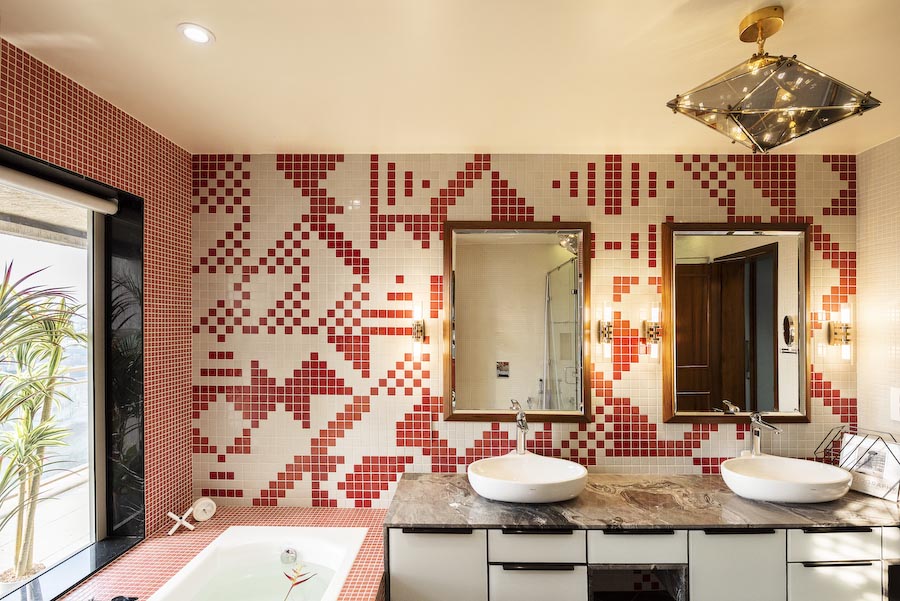 A bathroom with red and white patterned tiles, two wash basins and a tub