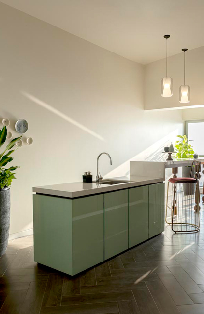 A kitchen with green cabinets and a a seating area next to it with high stools