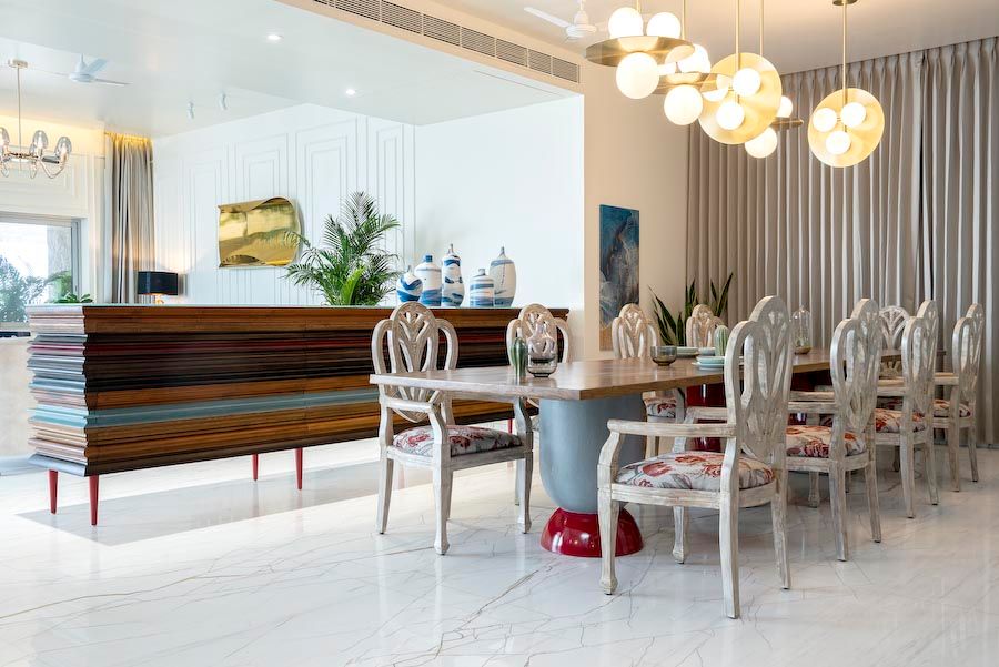 A dining room with a 12 seater solid wood table in teak and walnut sitting three cylindrical concrete legs along with a credenza next to it - Beautiful Homes