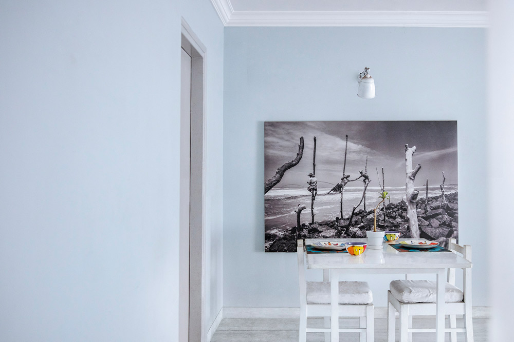 Print of fishermen stilt fishing adds up to the wall décor in this dining room design - Beautiful Homes