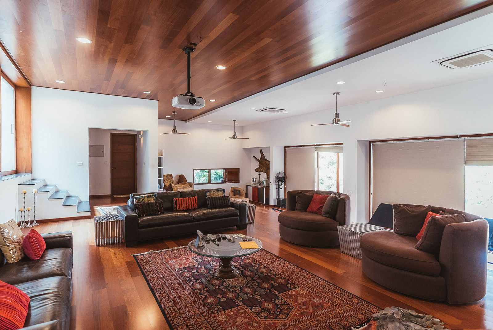 The living room in Rana’s home is a mix of warm woods, chocolate browns interspersed with hints of red - Beautiful Homes