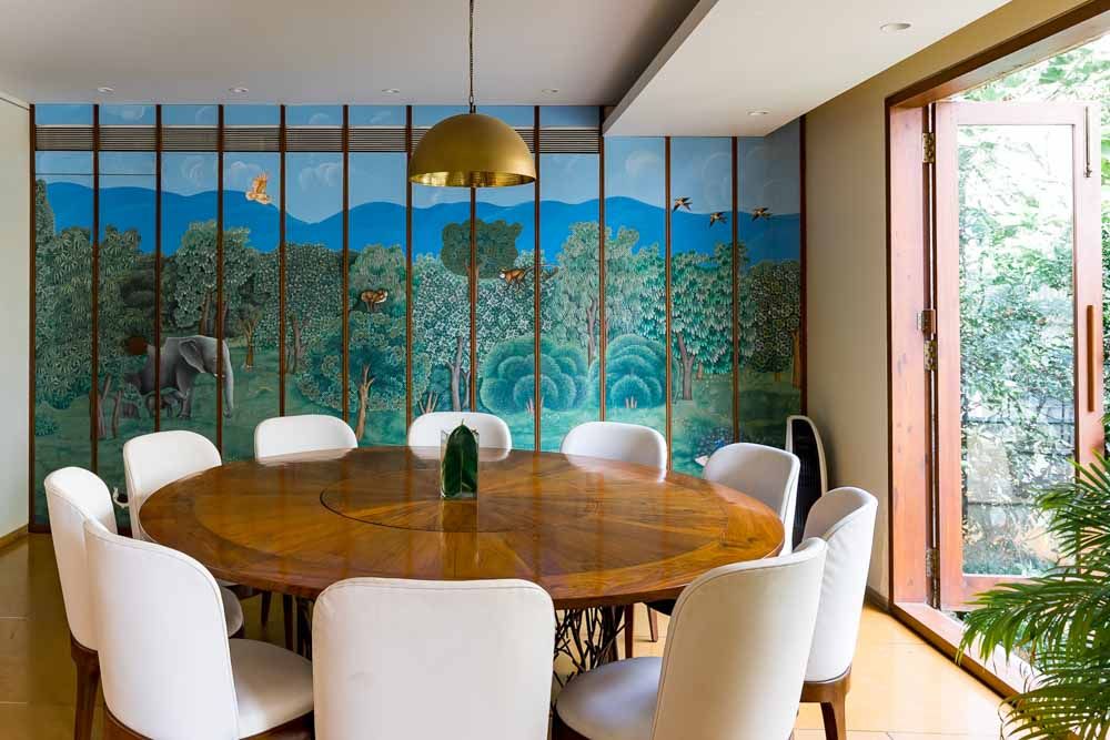 Dining area with a circular dining table, interesting wall design & windows opening outside of the house - Beautiful Homes