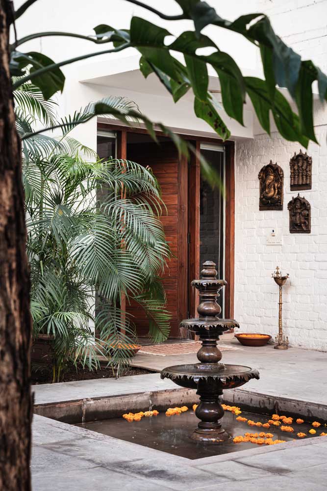 Traditional water fountain design with stone flooring & greenery outside the entryway - Beautiful Homes