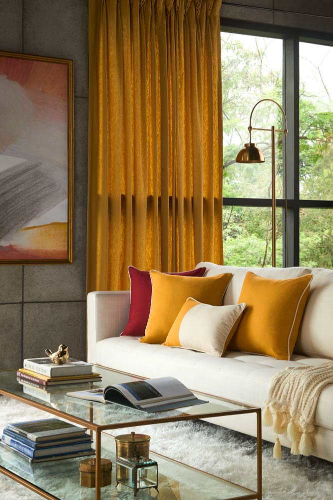 A living room with a white sofa and bright cushions  - Beautiful Homes