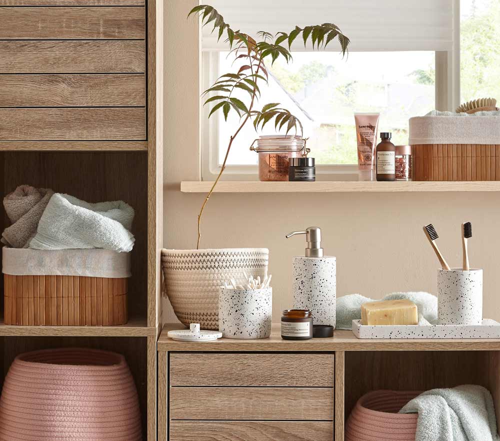 A bathroom with a basket with towels, a soap dispenser and a toothbrush holder - Beautiful Homes