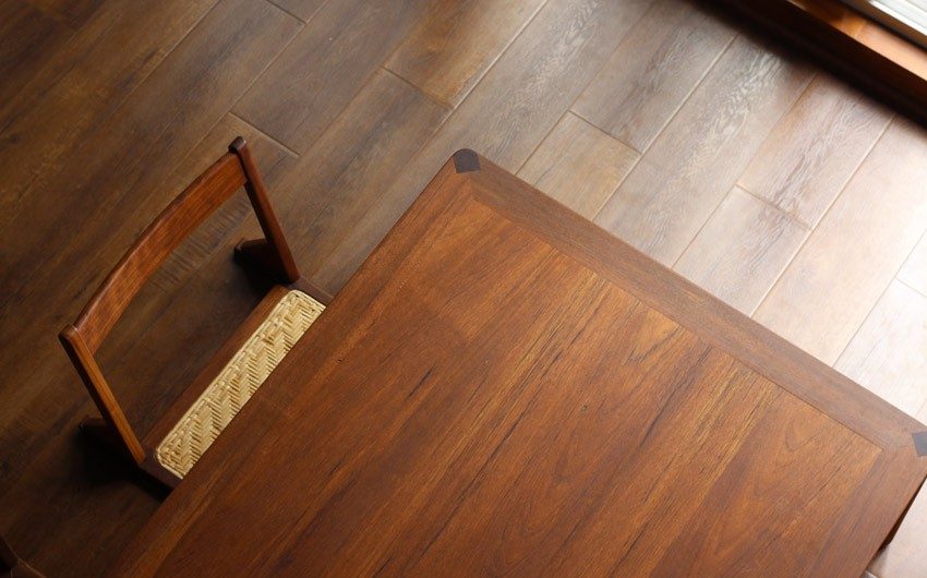 A low wooden table placed on a floor with a low chair placed along with the table