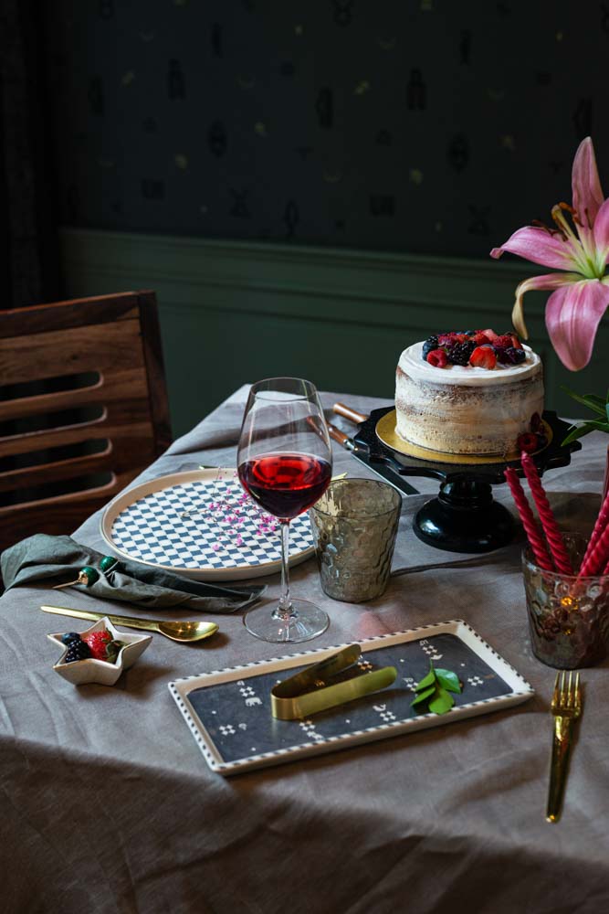 A cake kept alongside a plate and a wine glass