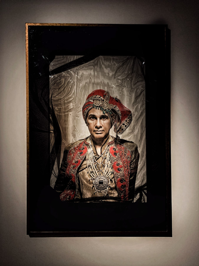 A framed photograph of a man wearing royal Indian clothes hung on a wall