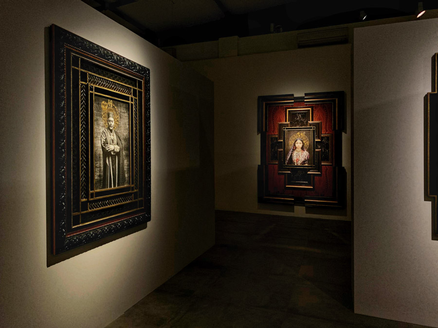 A couple of large frames of portraits hung on walls perpendicular to each other in a gallery